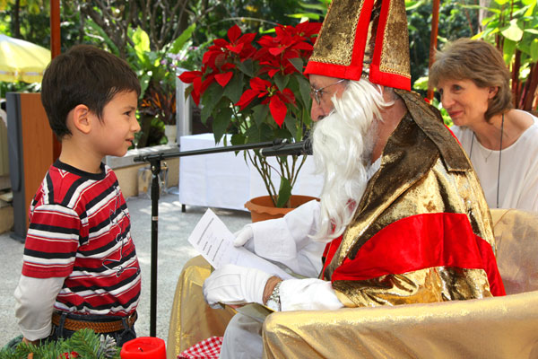 Der Nikolaus beschenkt einen kleinen Jungen in der Deutschen Botschaft in Bangkok