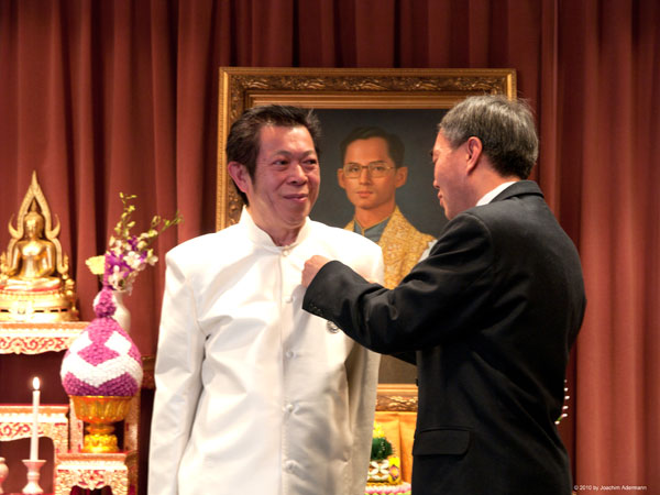 Thai-Gastronom und Journalist Edd bekommt vom Botschafter den Orden angesteckt.
