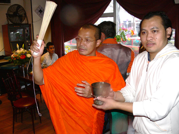 Der Mönch vom Wat Wittenau versprenkelt heiliges Wasser. DJ Geng hält die Schale mit dem Wasser.